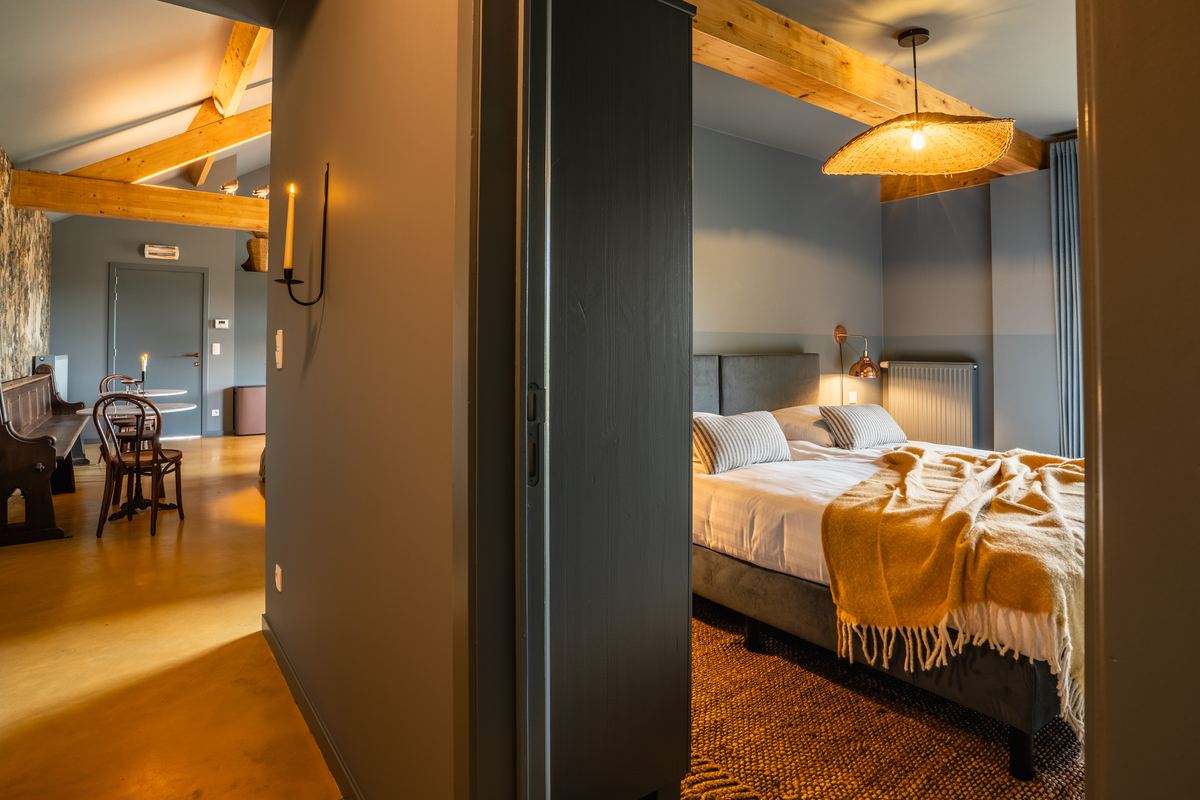 Doorkijk vanuit de gemeenschappelijke ruimte naar een slaapkamer met balkenplafond