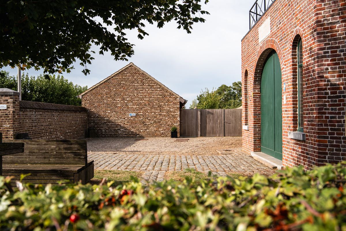 Het geplaveide erf met de groene poortdeur van de molen en de bijgebouwen