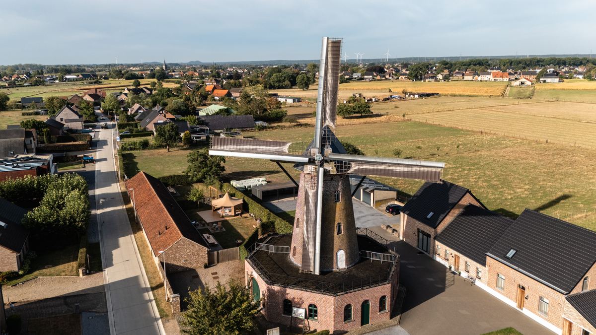 Luchtfoto van de molen boven de daken van Elen met de Maasvallei op de achtergrond
