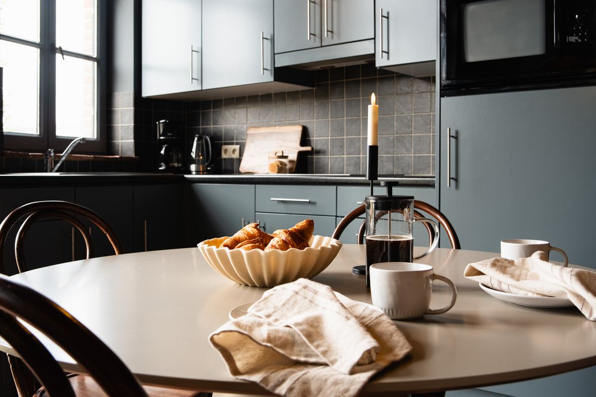 Croissants in een geribbelde schaal met cafetière en mokken op de ontbijttafel