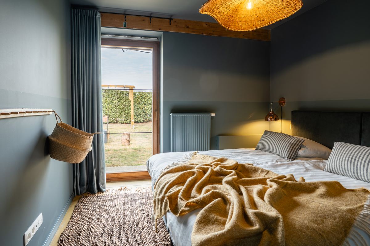 Slaapkamer met tuindeur, rieten hanglamp en gestreept beddengoed