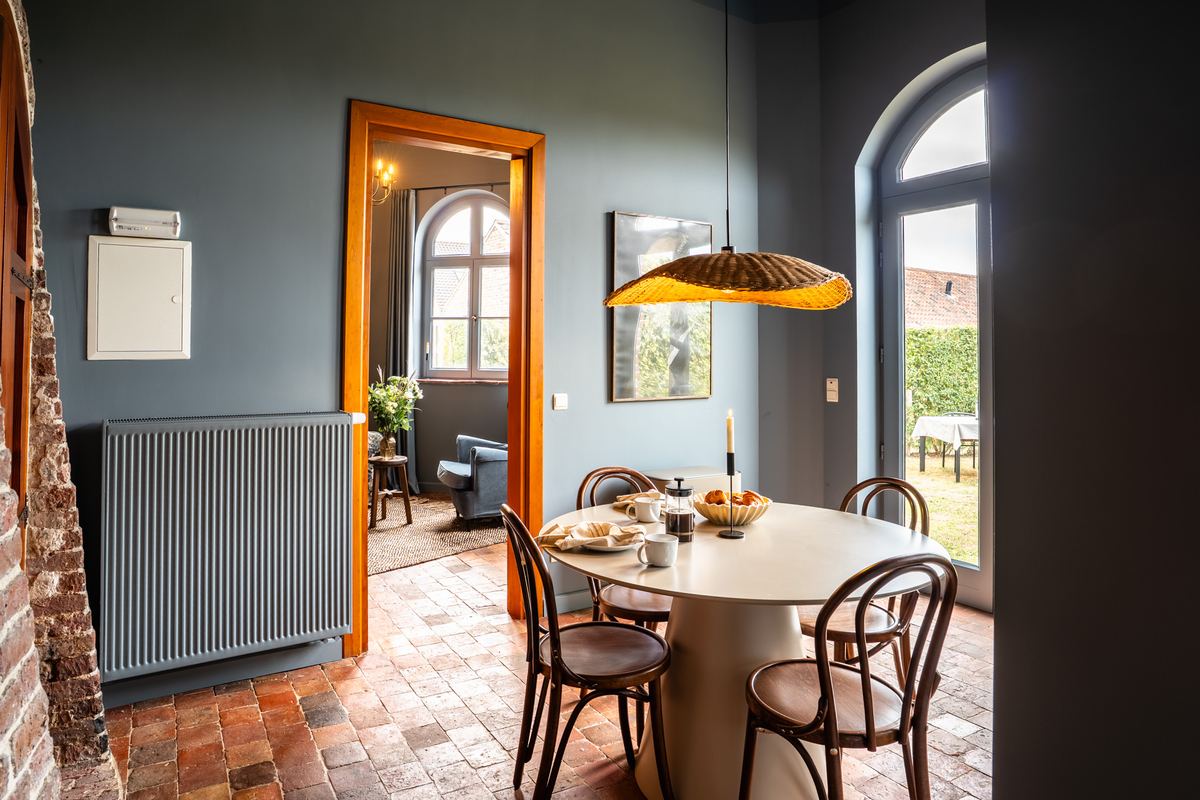 Eethoek met ronde tafel en doorkijk naar de zithoek op de terracotta vloer